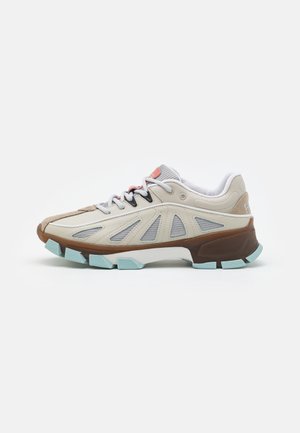 Beżowo-niebieski sneaker z grubą brązową podeszwą, siateczkowymi panelami bocznymi, białymi sznurowadłami i wyściełanym kołnierzem, zaprojektowany do noszenia na zewnątrz lub na co dzień.