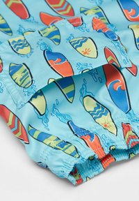 Swim trunks in light blue fabric featuring colorful surfboard patterns, with elastic waistband and stitched details.