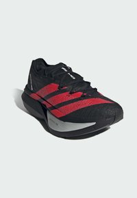 Black athletic shoe with red diagonal stripes, textured upper, prominent cushioning, and a gray sole labeled "LIGHTSTRIKE PRO."