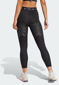 Černé legíny s texturovaným zebřím vzorem na lýtkách, vyrobené z elastického materiálu, s značkovým pasem a těsným střihem.