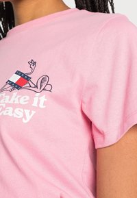 Růžové bavlněné tričko s krátkým rukávem, které na sobě má grafiku kreslené postavičky a bílý nápis "Take it Easy".
