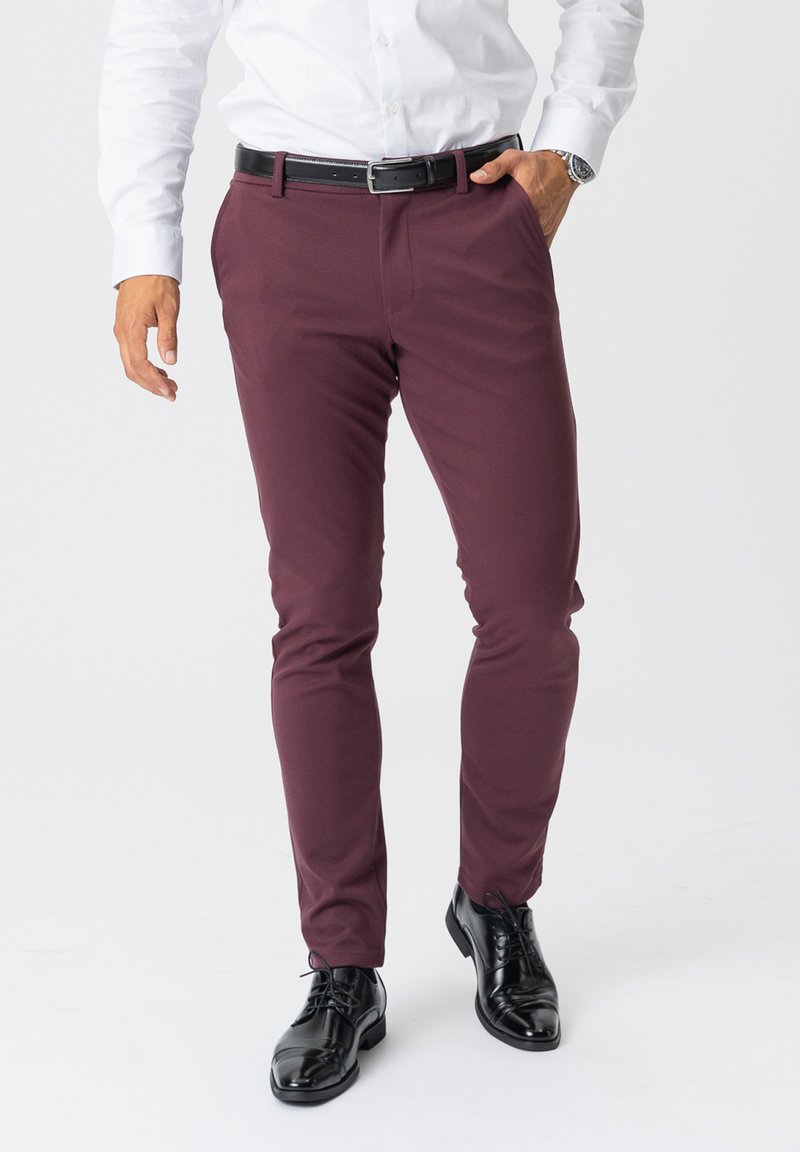 Bordeaux slim-fit bukser med glat tekstur, et sort bælte og skinnende sorte dress shoes. Crisp hvid skjorte med lange ærmer.