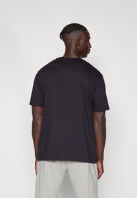 Sort bomulds T-shirt med korte ærmer og lige kant, vist fra bagsiden. Har rund halsudskæring og afslappet pasform.