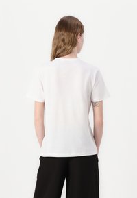 Tricou alb din bumbac, cu decolteu rotund, mâneci scurte și croi lejer. Textură fină, design minim, fără modele sau grafice vizibile.