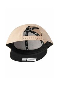 Il cappello presenta un corpo in tessuto beige, visiera nera e cinturino regolabile. L'interno mostra etichette di marchio in bianco e nero e una fodera in rete.