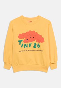 Κίτρινο φούτερ με μακριά μανίκια και παιχνιδιάρικη κόκκινη απεικόνιση σκύλου με το κείμενο «TINY 26 services de jardinage et d'entretien» στο εμπρόσθιο μέρος.