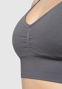 Grau Sport-BH mit V-Ausschnitt, elastischem Band am unteren Rand und gefälteltem Detail in der Vordermitte. Weiches, dehnbares Material.