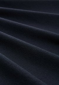 Tessuto blu scuro con una superficie morbida e testurizzata, caratterizzato da schemi sottili e delicati e pieghe lisce.