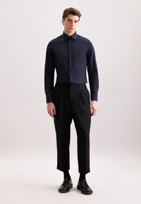 Granatowa koszula z długim rękawem, z klasycznym kołnierzykiem i zapinana na guziki, w połączeniu z czarnymi spodniami w kant i czarnymi butami eleganckimi.