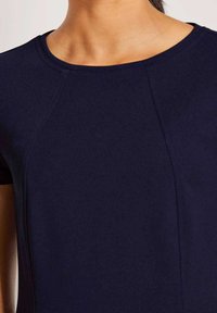 Navyblauw kortmouwen top met een ronde halslijn, gemaakt van gladde stof, met subtiele textuur en gestikte details langs de naden.