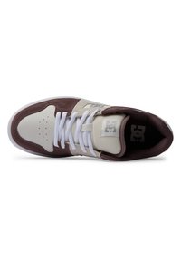 Baskets DC avec un bout en cuir blanc, des côtés en suède marron, des lacets blancs et une languette rembourrée avec le logo. Semelle en caoutchouc pour l'adhérence.