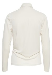 Bakifrån vy av långärmad, krämfärgad polotröja med mjukt tyg och subtila sömmar på vit bakgrund.