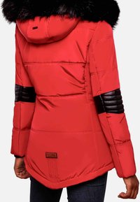 Rød pufferjakke med hætte af sort faux pels, ribbede sorte læderdetaljer på ærmerne og et logo-patch over sømmen.