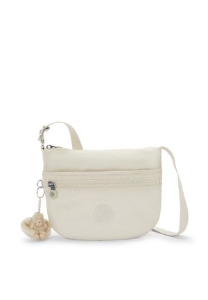 Beige crossbody bag made of soft fabric with a zip pocket and logo. It features a plush monkey keychain attached to the zipper pull.