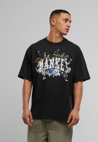 Sort bomulds T-shirt med korte ærmer, der har et farverigt grafiktryk af hockeyspillere og ordet "MARKET" tværs over brystet.