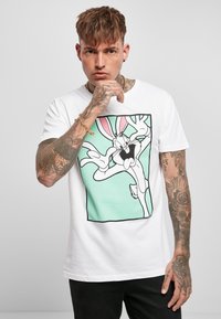 T-shirt bianco a maniche corte con grafica di un personaggio dei cartoni animati, su uno sfondo verde menta e contorni neri audaci.