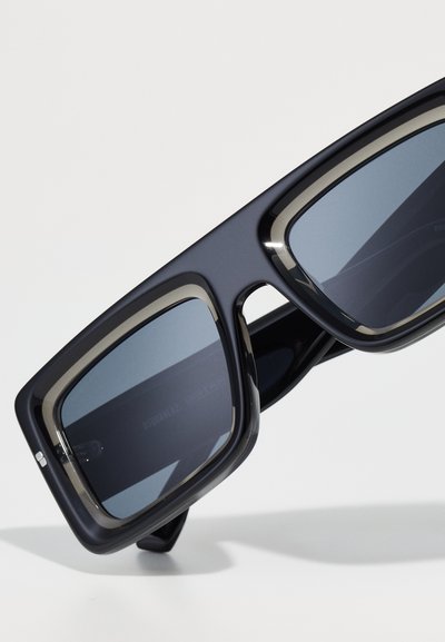Black plastic sunglasses with large rectangular lenses, grey tinted glass, and a matte finish. Features thin metallic accents along the edges.