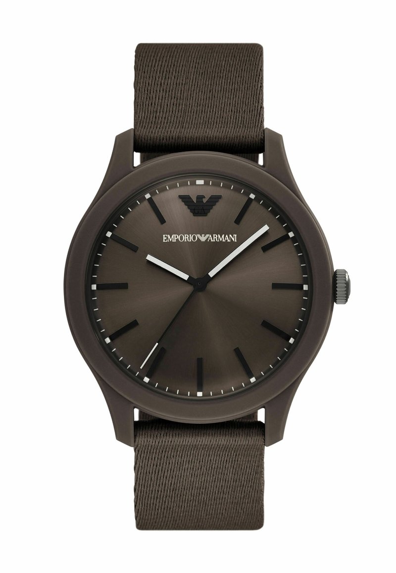 Reloj con correa de tela marrón y caja redonda de color marrón oscuro. La esfera presenta un efecto de rayos de sol, acentos plateados y un logotipo en la parte superior.