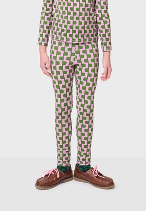 Leggins s geometrijskim uzorkom u zelenoj i ružičastoj boji, uskog kroja, rastezljivi materijal, nosi se s smešnim cipelama s ružičastim vezicama.