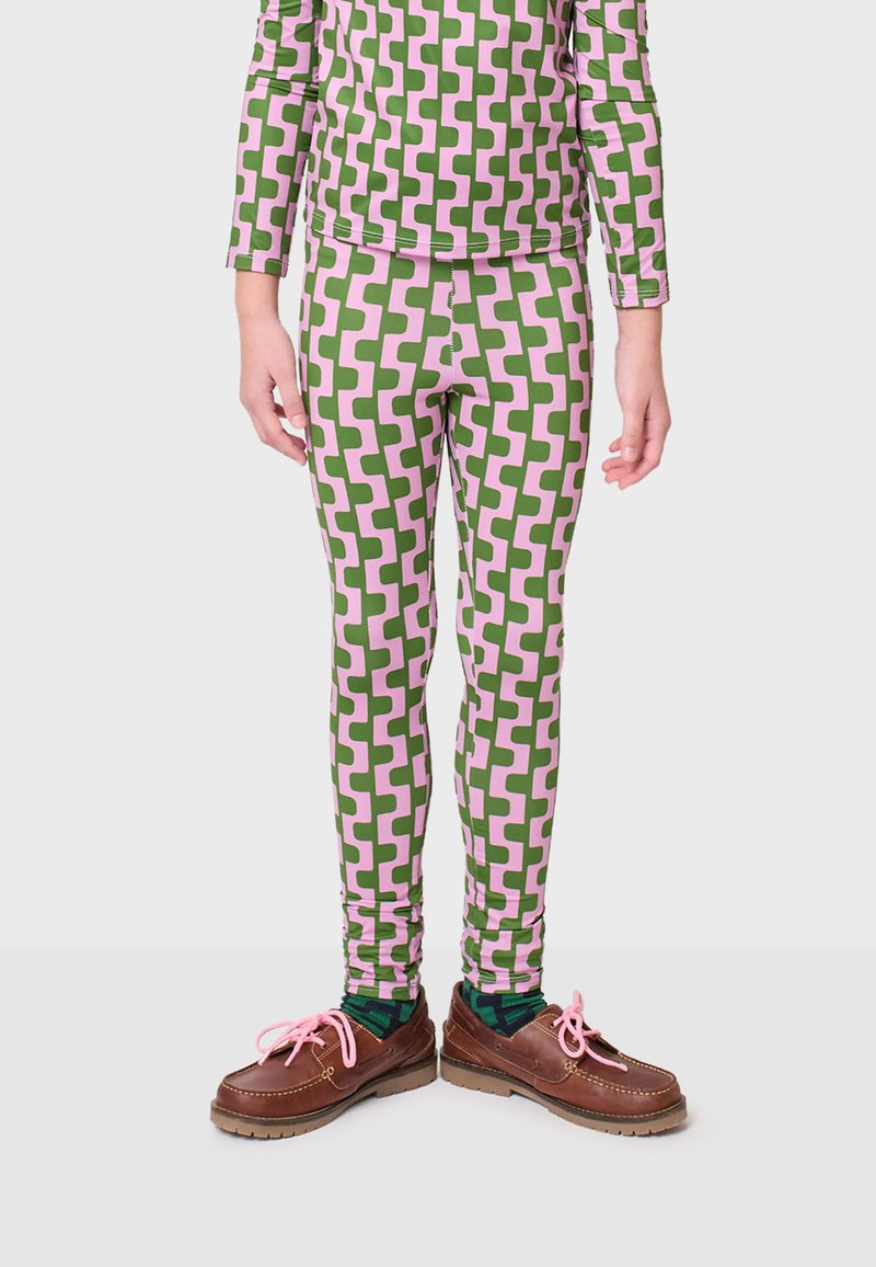 Legging met een geometrisch patroon in groen en roze, strakke pasvorm, rekbaar materiaal, gedragen met bruin schoenen met roze veters.