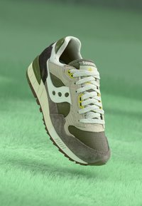 Zeleno-beige tenisky s priedušnými a semišovými materiálmi, s bielymi šnúrkami a akcentmi, štruktúrovanou podrážkou a kontrastnými žltými detailmi.