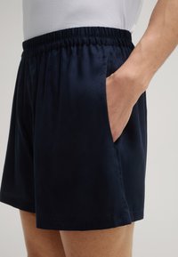 Shorts bleu marine avec taille élastique, comportant des poches latérales et un motif texturé subtil sur le tissu.