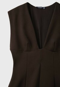 Robe ajustée sans manches marron foncé avec un profond décolleté en V et des coutures structurées au niveau de la poitrine et de la taille, étiquette visible à l'intérieur de l'encolure.