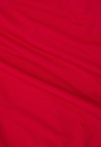 Czerwony bawełniany materiał o gładkiej fakturze, z subtelnymi zagnieceniami i fałdami. Kolor jest żywy i równomiernie rozłożony.