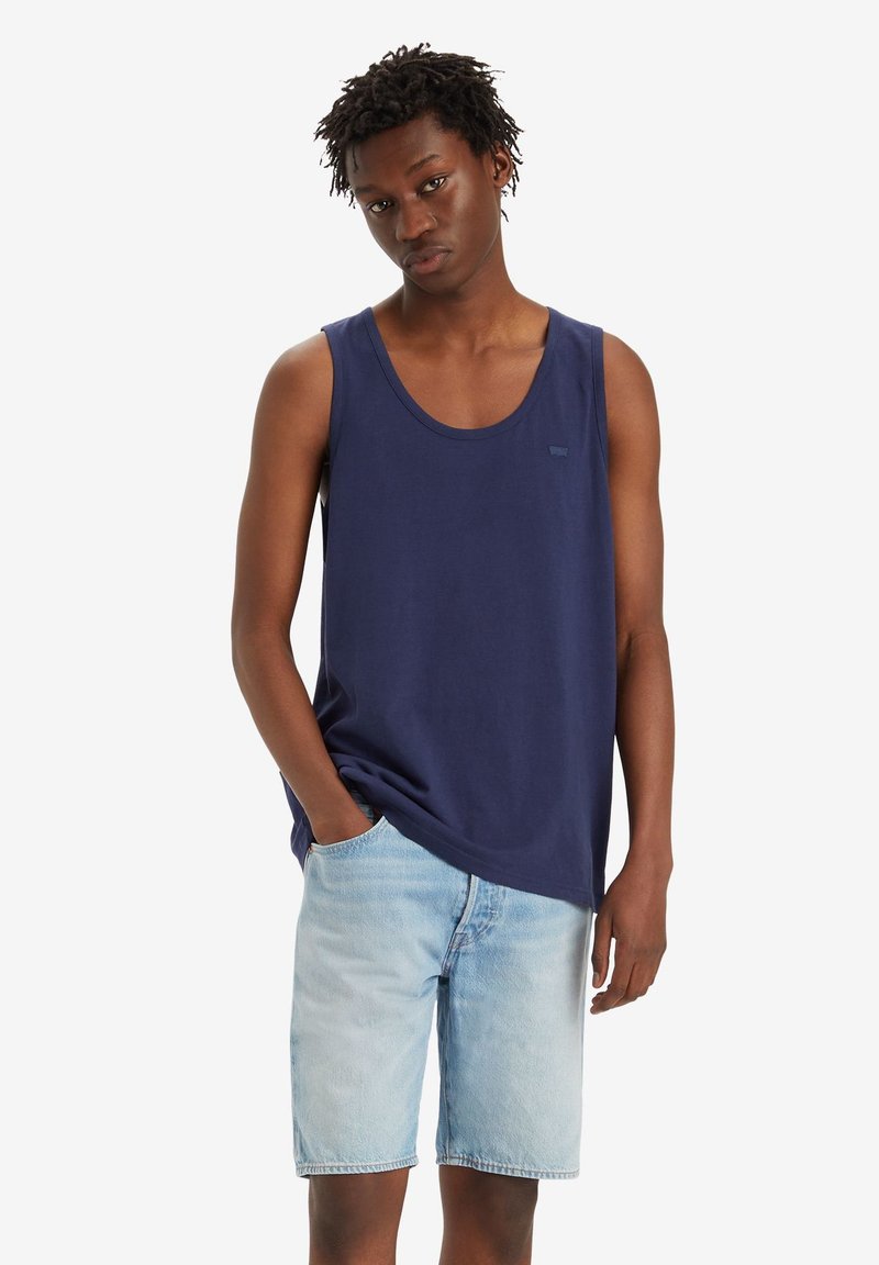 Top in cotone blu navy con scollo rotondo e vestibilità comoda, abbinato a pantaloncini di denim azzurri. Il tessuto è morbido e liscio.