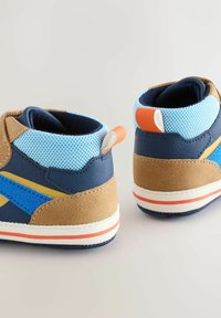 Baskets montantes bleues et brunes en suède et mesh, avec des accents orange et jaune, semelle blanche et forme arrondie.