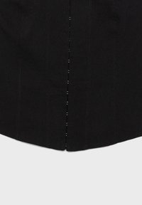 Tissu noir avec des détails de couture verticale et une fente centrale sur le bord inférieur, sur un fond gris clair.