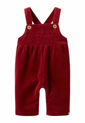 Crvene baršunaste kombinezone s podesivim križnim trakama i dva drvena gumba. Imaju kratke nogavice i naboran struk za lakše kretanje.