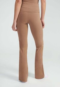 Bruine flare legging met een soepele textuur en een hoge tailleband. Heeft een effen kleur zonder patronen of versieringen.