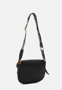 Černá prošívaná crossbody taška s embosovaným vzorem loga, se plátěným popruhem s nápisem "Guess" a zlatými kovovými detaily.
