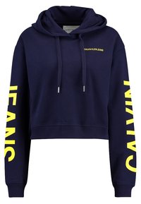 Marinblå kort hoodie med dragsnören, gul "CALVIN KLEIN JEANS" text på bröstet och stor gul text på ärmarna.