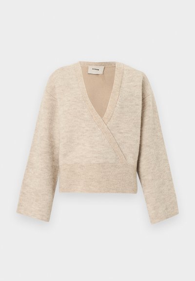 Μπεζ cropped πουλό βερ πλεκτό με στυλ περιτυλίγματος, μακριά μανίκια και φαρδιά ριμπ ζώνη στη μέση, με ετικέτα "Aeron" στο εσωτερικό του λαιμού.