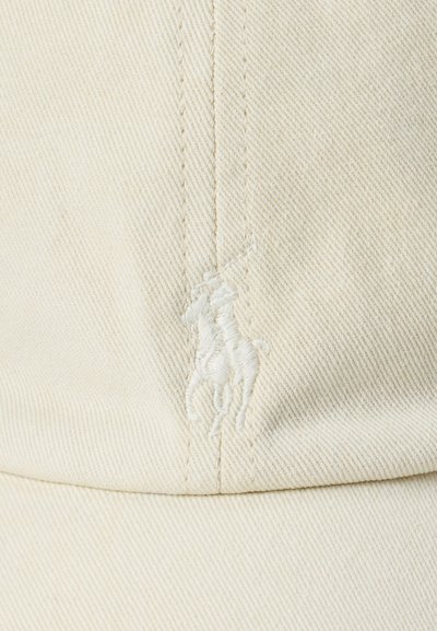 Casquette en coton blanc avec une surface texturée, présentant un logo brodé ton sur ton d'un cavalier. Forme structurée avec des détails de couture.