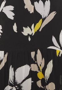 Černá látka s velkými abstraktními květinovými vzory v bílé, béžové a žluté barvě. Vrásečková textura na spodní části dodává detail.