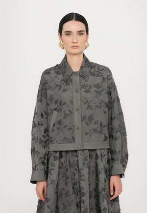 Graue Jacke mit floralen Stickereien, Kragen und Druckknöpfen, im cropped Design und mit elastischen Bündchen. Gemusterter Stoff.