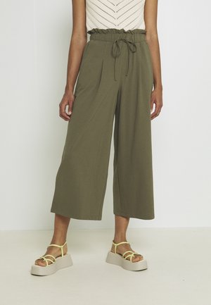 Person wearing high-waist olive green wide-leg pants with drawstring and cream platform sandals with thin straps.
