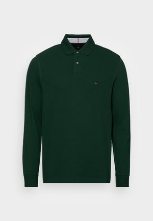 Donkergroene lange mouwen polo met twee knopen op de knopenlijst en een klein rood, wit en blauw logo op de borst.