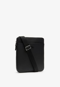Borsa a tracolla nera con esterno testurizzato, forma rettangolare, tracolla regolabile e chiusura a zip. Presenta un sottile logo del marchio sul davanti.