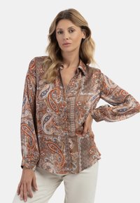 Blusa di seta a maniche lunghe con motivo paisley in toni di arancione, blu e marrone, dotata di chiusura a bottoni e colletto classico.