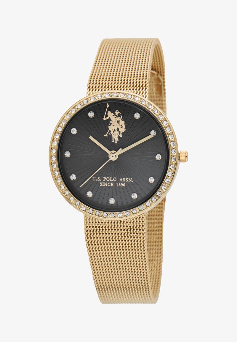 Montre avec bracelet en maille dorée et cadran texturé noir, rehaussée de cristaux transparents, avec aiguilles et logo dorés. Design de boîtier circulaire.