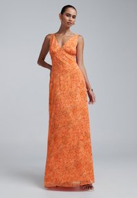 Maxi obleka v svetlo oranžni cvetlični vzorcu, z V-izrezom in prilegajočim pasom. Gladka tekstura, brez rokavov in tekoča krila.