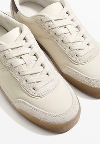 Beiget tennarit, joissa yhdistyvät sileä nahka ja teksturoitu mokkanahka. Nauhoina vaaleanbeige kangas, kumipohja ja hillityt ompelusomisteet.