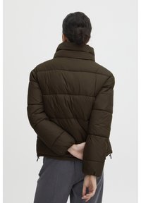 Dunkelgrüne, gesteppte Pufferjacke mit hohem Kragen, elastischen Bündchen und seitlichen Reißverschlüssen. Der Stoff wirkt weich und isoliert.
