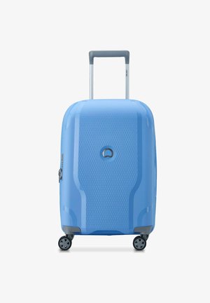 Maleta dura azul con superficie texturizada, mango retráctil y cuatro ruedas. Presenta un logo circular y detalles en cremallera plateados.