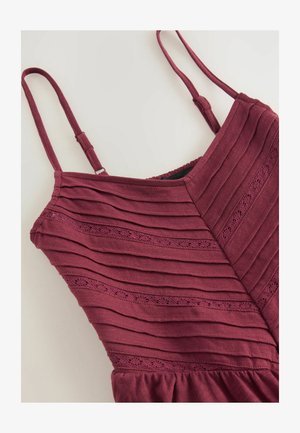 Burgundia kleit, millel on vertikaalne ribatekstuur, õhukesed rihmad ja dekoratiivne aasa muster rinna lähedal. Ümaral äärelõikega allservas.