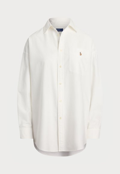 Balts pogu krekls, izgatavots no kokvilnas, ar krūšu kabatu un mazu izšūtu logotipu. Brīvs piegriezums ar klasisku apkakli un garām piedurknēm.